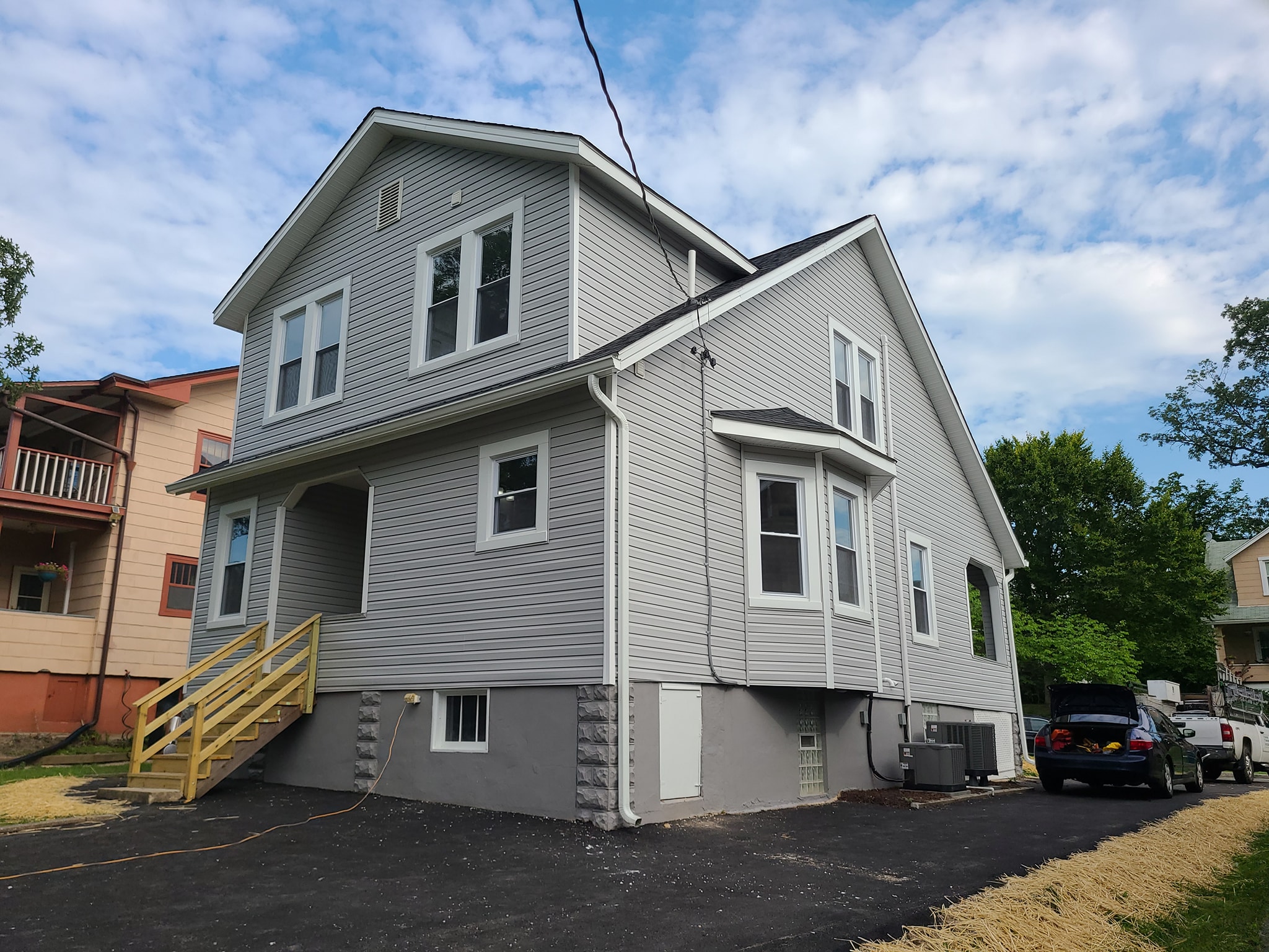 Two-story home with new light gray siding, white-trimmed windows, and bay window