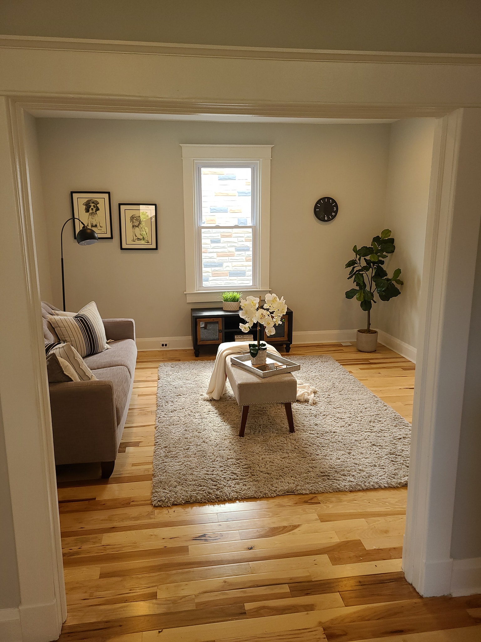 Living room with white door and window trim, hardwood floors, and neutral décor