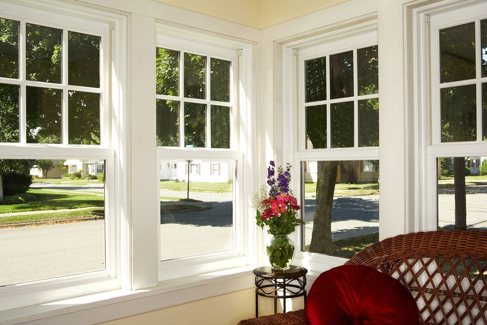Sunroom with four white double-hung windows and traditional grilles in the top sashes overlooking a residential street